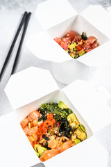 Wok noodle in paper box with vegetables , salmon and tuna. street food to go, take away.  White background. Top view