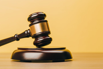 Judge Gavel on a wooden table and yellow-orange background.