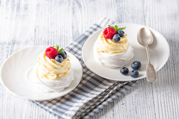 Romantic spring breakfast. Pavlova cakes with cream and fresh summer berries. Soft focus