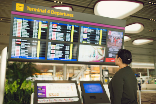 An Air Traveler Views A Flight Notice Board In The Departures Terminal Of Airport