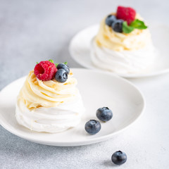 Pavlova cakes with cream and fresh summer berries. Soft focus
