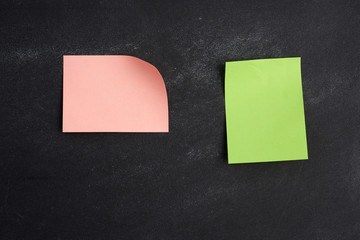 blank pink and green paper sticker glued on a black board