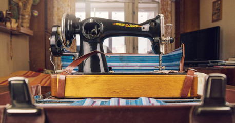 black shiny vintage sewing machine ready to work on wooden table in apartment