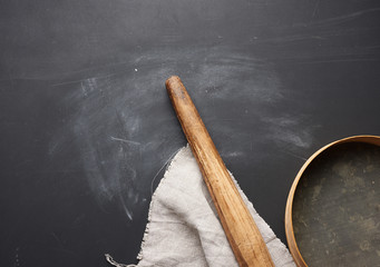 wooden rolling pin and a round sieve lie on a gray linen napkin, black table