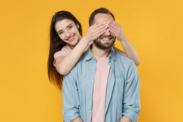 Smiling young couple two friends guy girl in pastel blue casual clothes posing isolated on yellow background studio portrait. People lifestyle concept. Mock up copy space. Covering eyes with hands.