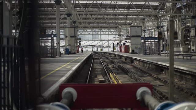 50mm creative shot of London Underground station during Covid-19 virus lockdown. View of traintrack through bars. Shot gliding lefwards. Just one person in distance on the platform. Eery and quiet.