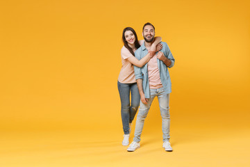 Funny young couple two friends guy girl in pastel blue casual clothes posing isolated on yellow wall background studio portrait. People lifestyle concept. Mock up copy space. Hugging, looking camera.