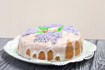 Lavender Cupcake. Sugar coated. Decorated with lavender glaze flowers. A small piece is cut off.