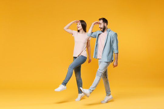 Excited Young Couple Two Friends Guy Girl In Pastel Blue Casual Clothes Posing Isolated On Yellow Wall Background. People Lifestyle Concept. Holding Hand At Forehead Looking Far Away Distance Walking.