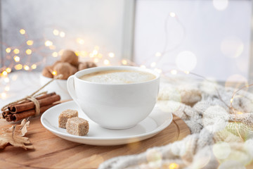 Cozy autumn composition with cup of coffee knitted scarf and garland. Hygge concept