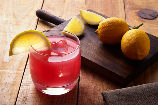 Pomerade and lemon citric mocktail. Alcohol free cocktail. Concept of refreshing drink served in a summer beach bar. Wooden background next to several cut citrus fruits on a table.