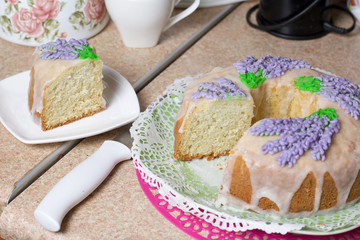Lavender Cupcake. Sugar coated. Decorated with lavender glaze flowers. A small piece is cut off.