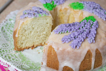 Lavender Cupcake. Sugar coated. Decorated with lavender glaze flowers. A small piece is cut off.