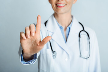 Smiling female doctor presses virtual button on the screen.