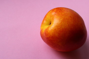 nectarine fruit, peach on a pink background