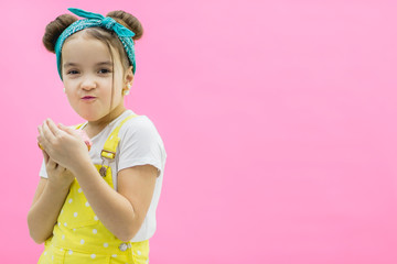 Little girl is eating a donut on a colored background.