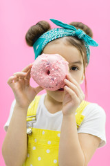 Little girl wearing bandage hiding behind a donut.