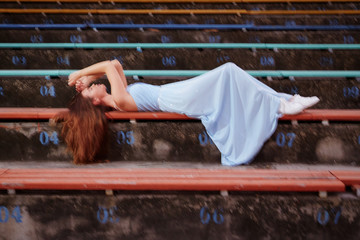 Full length portrait of beautiful caucasian woman laying on the stair of the stadium with pink background