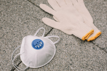 Mask, gloves are lying on the grey table background. Glass of water is standing on the grey background. Safety.