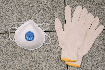 Mask, gloves are lying on the grey table background. Glass of water is standing on the grey background. Safety.