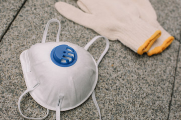Mask, gloves are lying on the grey table background. Glass of water is standing on the grey background. Safety.