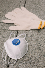 Mask, gloves are lying on the grey table background. Glass of water is standing on the grey background. Safety.