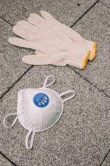 Mask, gloves are lying on the grey table background. Glass of water is standing on the grey background. Safety.