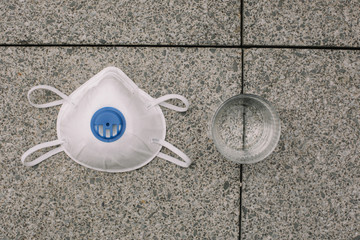Mask, gloves are lying on the grey table background. Glass of water is standing on the grey background. Safety.
