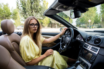 Beautiful girl driving a car.Portrait of the beautiful young girl on nature with cabriolet.Blonde...