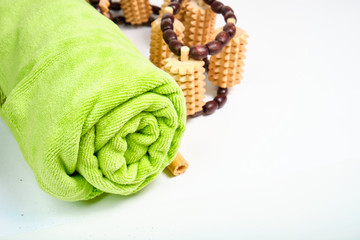 Green towel and wooden massager on white background
