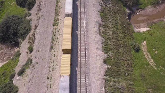 Freight Train crossing a highway bridge with traffic passing below, Top down aerial view.