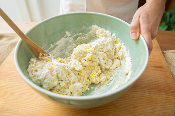 Baker kneading ingredient and wheat flour with wooden spoon in ceramic bowl. Dough preparation for delicious pastry and bread. Studio shot. Angled view. Homemade food and nutrition concept