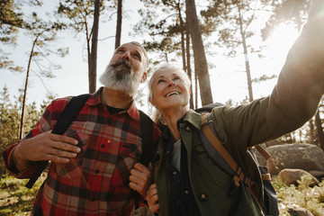 Active happy senior couple hiking together in forest and exloring nature
