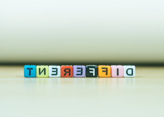 DIFFERENT word written in  cube on wooden floor on white background, letter blocks arranges into DIFFERENT words, for adding text or other images or design