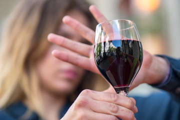 Woman with hand gesture refusing glass of wine or alcohol.