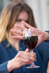 Woman with hand gesture refusing glass of wine or alcohol.