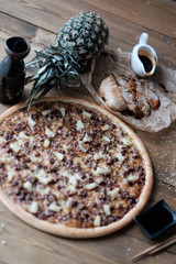 Fototapeta premium Pizza with a meat and pineapple with ingredient on the wooden table in rustik style