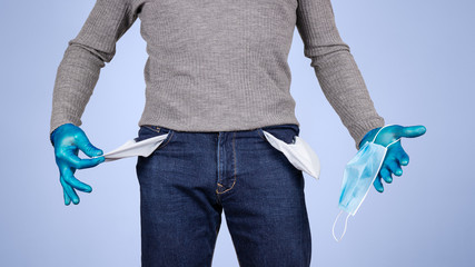 Male half body view. Protected man with gloves and surgical mask, shows the pockets of his empty pants. Concept of crisis and economic recession caused by coronavirus and covid-19.