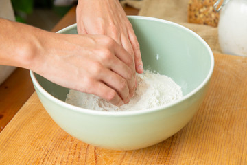 Hands touching wheat flour in ceramic bowl. Dough preparation for delicious pastry. Studio shot. Side view. Homemade bakery and nutrition concept