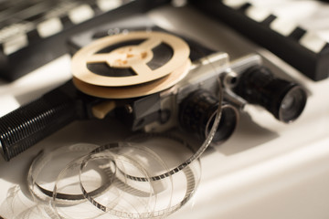Film roll with movie camera and movie clapper board on light backlit table