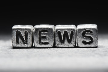 The concept of news. Inscription on metal 3D cubes isolated on a black background, grunge style