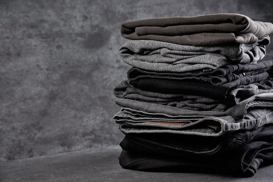 A stack of neatly folded dark clothes isolated on a black gray background close-up