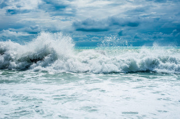 Storm waves on the ocean against a turquoise sky and clouds. Surf