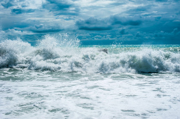 Storm waves on the ocean against a turquoise sky and clouds. Surf