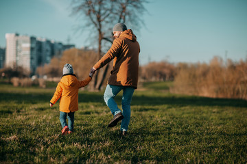 Father and daughter playing in park on green grass. Father's day. Little girl plays with dad outside.