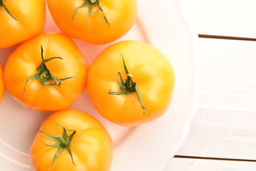 Fresh juicy organic yellow tomatoes, close-up, on a painted wooden table.