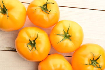 Fresh juicy organic yellow tomatoes, close-up, on a painted wooden table.
