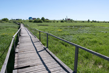 Fototapeta na wymiar Wooden pathway over a swampy area between Staroye Rakomo and Novoye Rakomo villages (Lake Ilmen region), Novgorod Oblast, Russia.