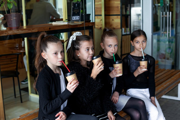 Group of female preteen kids  communicate together outdoor and drinking warm coffee drink in takeaway paper glasses
