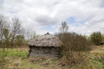 Kudrichi, Belarus 04/27/2020: Old houses and sheds with a roof covered with reeds using old-fashioned technology in the Polesie region in the south-west of Belarus.